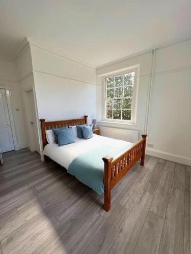 a bedroom with a bed with blue pillows and a window at The Beeches - Entire Mansion in Bristol