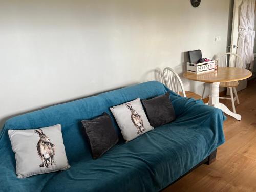 a blue couch with pillows on it in a living room at Kabin in the woods with Hot Tub in Llandybie