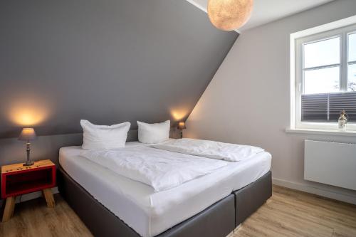 a white bed in a room with a window at Reetdachhaus Ahoi Reetdachhaus Ahoi in Tating