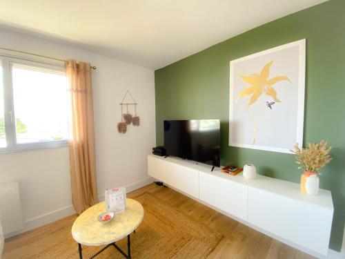 een woonkamer met een flatscreen-tv en een tafel bij Le Studio Calaisien in Calais