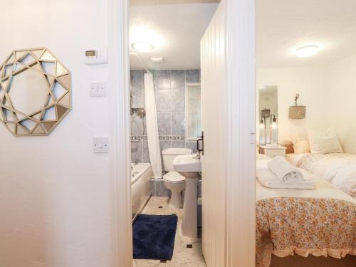 a bedroom with a bed and a bathroom with a sink at Meadow Cottage in Kendal