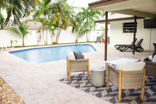 a patio with a swimming pool with chairs and a table at Blu Sky Villa in Boynton Beach