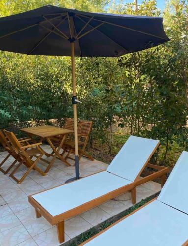 2 sedie e un ombrellone su un patio di Mini-Villa climatisée Porto-Vecchio a Porto Vecchio