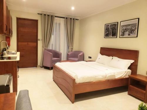 - une chambre avec un lit et deux chaises violettes dans l'établissement Le Cottage Mbale, à Mbale