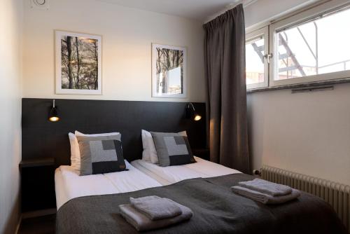 a bedroom with two beds and two windows at Hotel Bishops Arms Mora in Mora