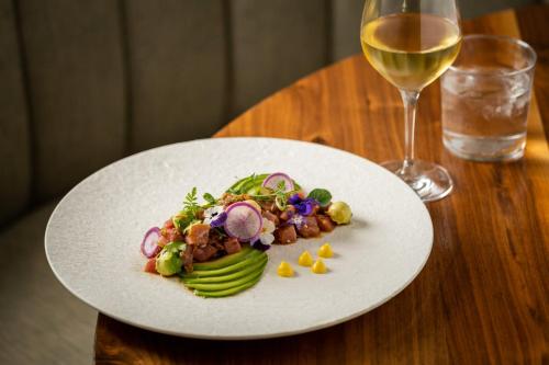 a plate of food on a table with a glass of wine at Kimpton Canary Hotel by IHG in Santa Barbara
