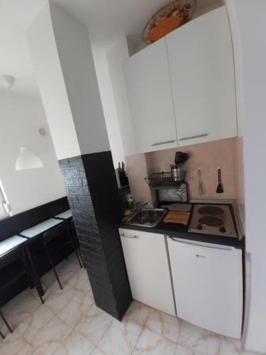 Elle comprend une petite cuisine avec des placards blancs et un évier. dans l'établissement Keti 2, à Belgrade