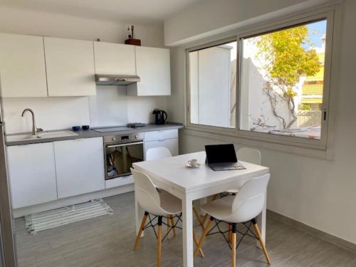 una cocina con una mesa blanca y un ordenador portátil. en Arthur Properties Rue d'Antibes, en Cannes