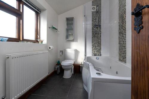a bathroom with a tub and a toilet and a sink at The Coach House in Penmachno