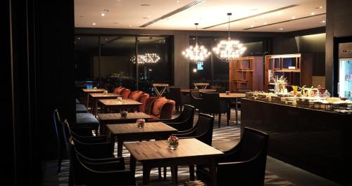 a restaurant with wooden tables and chairs and chandeliers at G Hotel Kelawai in George Town