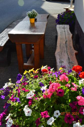 einen Blumengarten mit einem Holztisch und Blumen in der Unterkunft Gasthof zum Herzog 