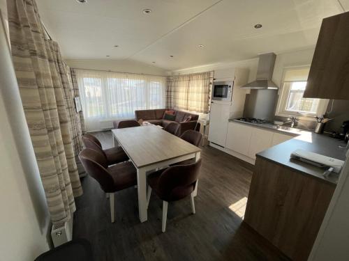 a kitchen and a living room with a table and chairs at Chalet (A16) op gezellige familiecamping bij zee in Kamperland