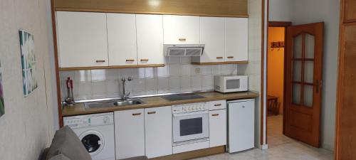 a kitchen with white cabinets and a sink and a microwave at Apartamentos Lausan in Gavín
