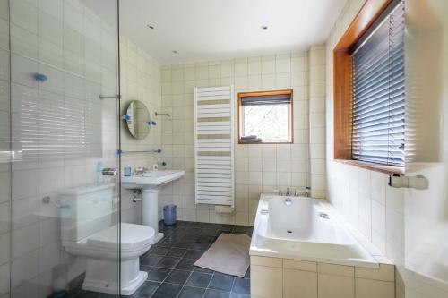 y baño con aseo, bañera y lavamanos. en Large contemporary house with indoor swimming pool, en La Gaudaine