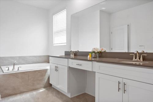 a white bathroom with a sink and a bath tub at Modern Resort House Pool Wi-Fi Minutes to Disney in Kissimmee