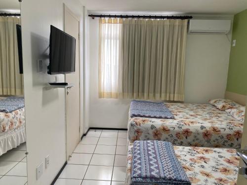 a hotel room with two beds and a flat screen tv at Gran Lençóis Flat Residence in Barreirinhas