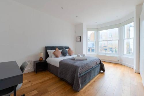 a white bedroom with a bed and a piano at Trendy East London Flat BRO1 in London