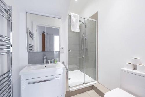 baño blanco con ducha y lavamanos en Trendy East London Flat BRO1, en Londres