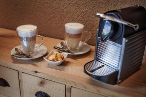 a table with two cups of coffee and a toaster at Hotel-Restaurant Burgseeli in Goldswil
