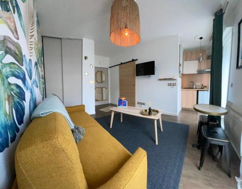 un salon avec un canapé jaune et une table dans l'établissement STUDIO de charme COSY BED, LA ROCHELLE, à La Rochelle