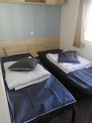 two beds sitting next to each other in a room at MHVACANCES LOUENT PLUSIEURS MOBILHOMES DANS CAMPING 4 ETOILES PROCHE CHATEAUX et ZOO BEAUVAL in Onzain
