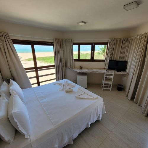 a bedroom with a white bed and a desk and windows at RANCHO GOSTOSO POUSADA in São Miguel do Gostoso