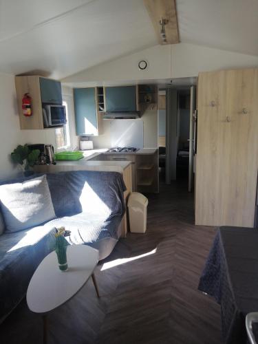 a living room and kitchen with a couch and a table at MHVACANCES LOUENT PLUSIEURS MOBILHOMES DANS CAMPING 4 ETOILES PROCHE CHATEAUX et ZOO BEAUVAL in Onzain