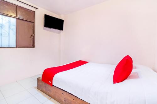 a bedroom with a white bed with red pillows and a window at OYO Hotel La Luna in San Cristóbal de Las Casas