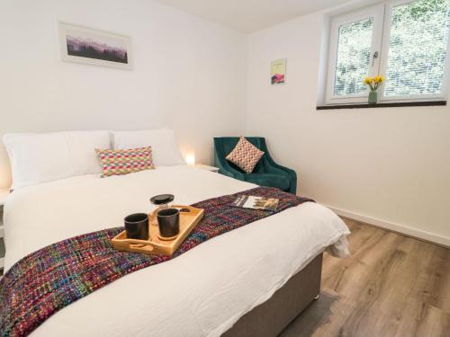 Un dormitorio con una cama y una bandeja con dos tazas. en Tŷ Capel Bach, en Bangor