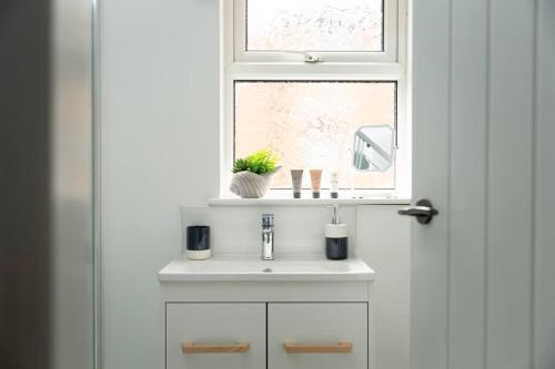 uma casa de banho com um lavatório branco e uma janela em High Tide - Filey apartment close to beach em Filey