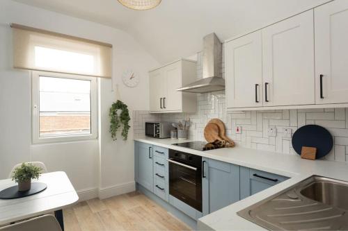 eine Küche mit weißen Schränken und einer Spüle in der Unterkunft High Tide - Filey apartment close to beach in Filey