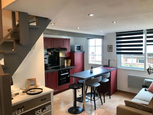 une cuisine avec des placards rouges et une table avec des tabourets dans l'établissement Appartement Duplex Cosy au calme à 50m de la plage, à Houlgate