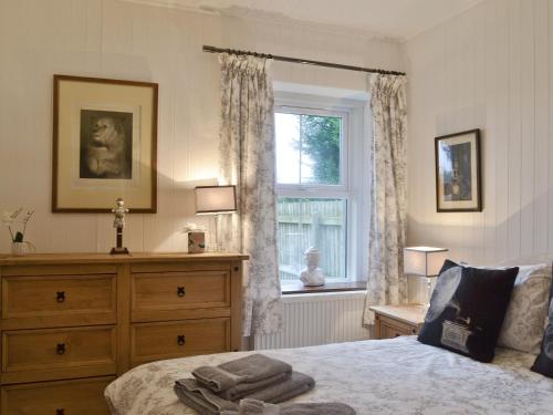 a bedroom with a bed with a dresser and a window at The Retreat in Belladrum