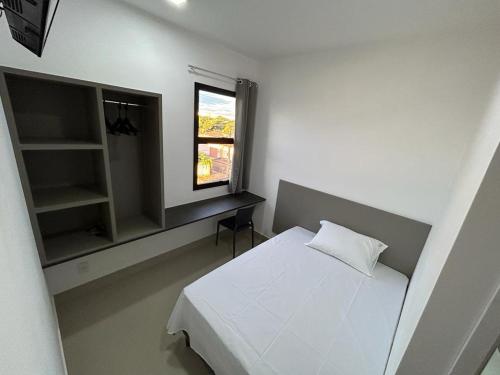 1 dormitorio con cama blanca y ventana en NANO Suítes, en Uberlândia