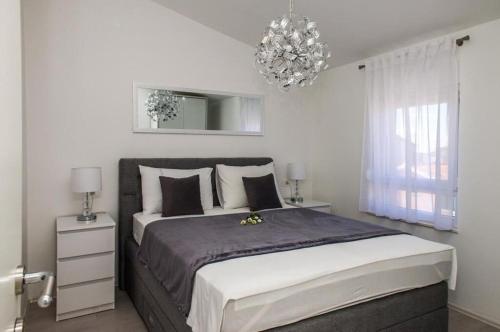 a bedroom with a large bed and a chandelier at Apartments Zdeslav in Rogoznica