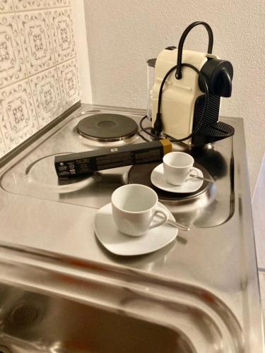a glass table with two coffee cups and a toaster at Garni Villa Siesta Park in Losone