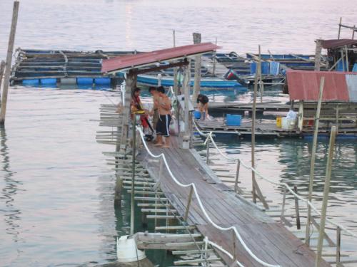 a group of people standing on a dock in the water at Pangkor Fish House in Pangkor