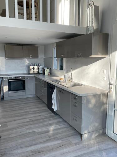 una grande cucina con elettrodomestici in acciaio inossidabile e armadietti grigi di La petite maison de Vence a Vence
