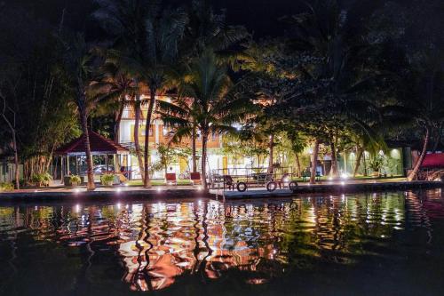 a pool of water with palm trees and a building at River Inn in Matara