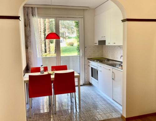 a kitchen with red chairs and a table and a window at Garni Villa Siesta Park in Losone