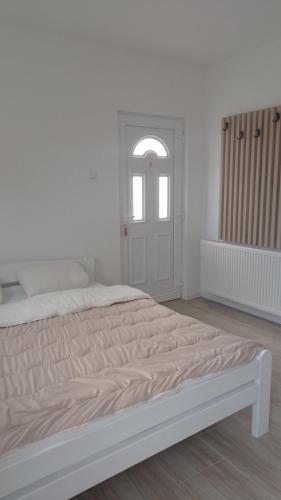 a white bedroom with a bed and a window at Apartman Milena Temerin in Temerin