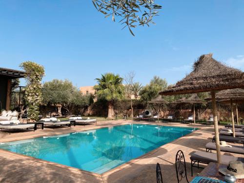 einen Pool mit Stühlen und Sonnenschirmen in einem Resort in der Unterkunft Villa Singulière By Louhou Collection in Marrakesch