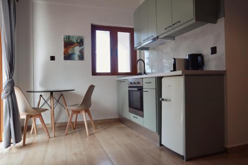 a kitchen with white cabinets and a table and chairs at Villa Elea Apartments in Spiliá