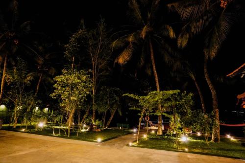 a park at night with palm trees and lights at River Inn in Matara