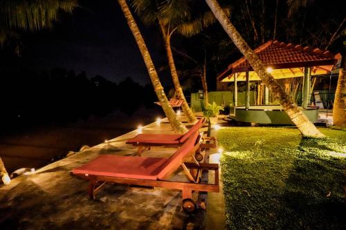 two chairs and a table on a swing at night at River Inn in Matara