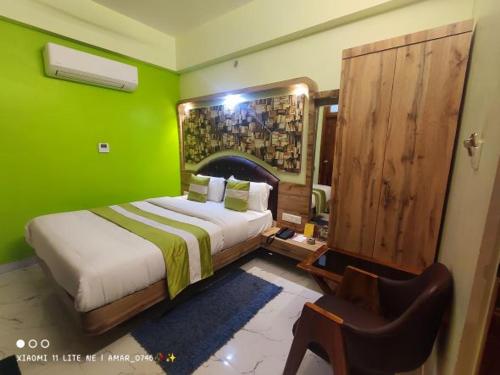 een groene slaapkamer met een bed en een stoel bij Hotel Prabhat in Varanasi