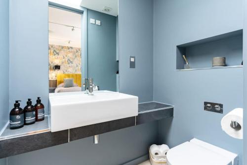 baño con lavabo blanco y pared azul en Luxury Water Tower I Roof Bar I Cinema, en Cardiff