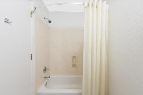 a bathroom with a white tub and a shower curtain at Super 8 by Wyndham Southaven in Southaven