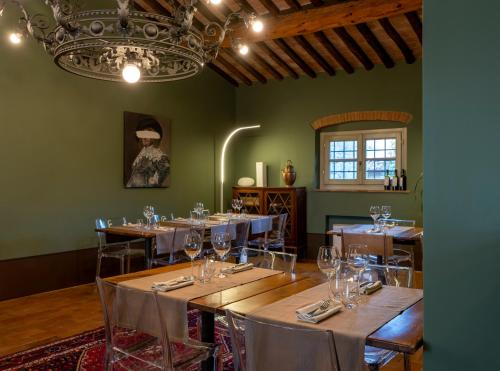 una sala da pranzo con tavoli e sedie e un lampadario di Agriturismo San Rocco a Pistoia