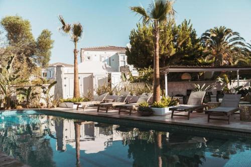 a swimming pool with chairs and palm trees next to a house at ARTOTEL in Alaçatı